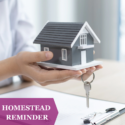 Tiny gray house being help in the palm of a women’s hands with a key and a office clipboard beneath. “Homestead Reminder” in purple header